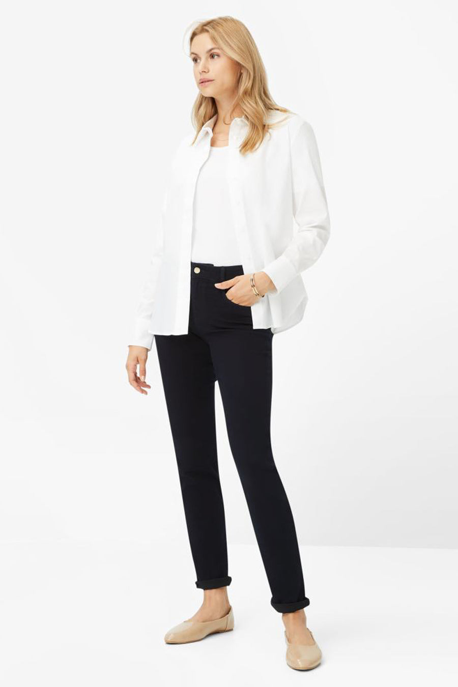 Jean slim en denim bleu noir de Brax, porté avec un t-shirt et une chemise blancs et des chaussures plates couleur chair.