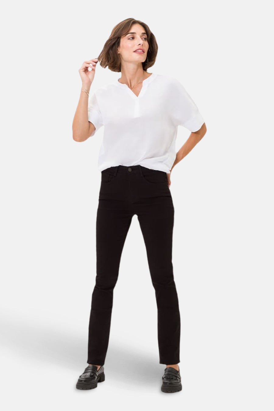 Zwarte rechte jeans van BRAX, gedragen met een witte blouse en zwarte schoenen met dikke zolen.