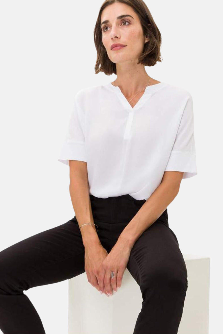 Zwarte rechte jeans van BRAX, gedragen met een witte blouse en zilveren sieraden.