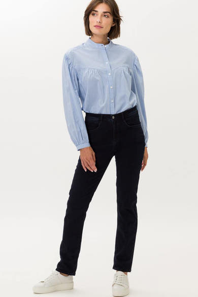 Donkerblauwe rechte jeans van BRAX, gedragen met een gestreept overhemd en witte sportschoenen.