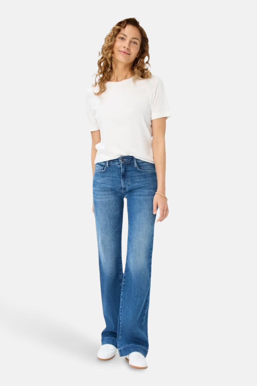Jean large en denim bleu moyen de BRAX, porté avec un t-shirt blanc uni et des baskets blanches.