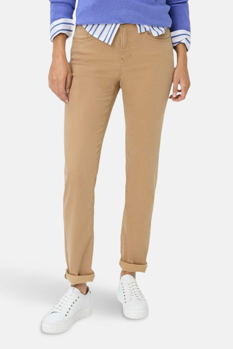 Rechte beige spijkerbroek van Brax, gedragen met witte sportschoenen en een blauwe trui.