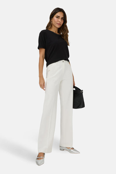 Pantalon de costume blanc de BRAX, coupe ample et jambes larges, porté avec un t-shirt noir et des chaussures argentées.