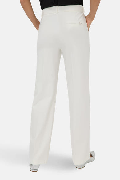 Pantalon de costume blanc de BRAX, coupe ample, avec des poches latérales et ourlet tombant sur des chaussures argentées.
