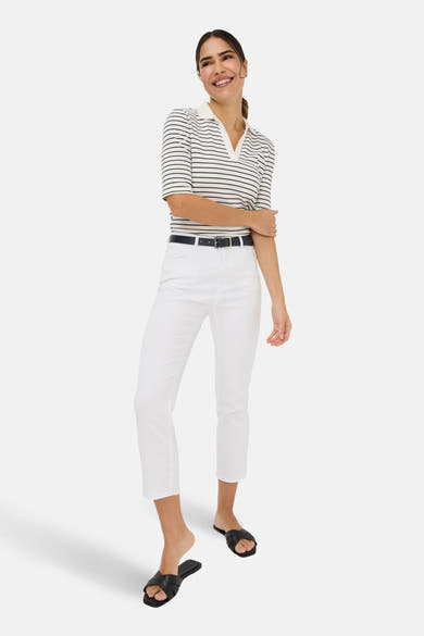 Jean slim en denim blanc de BRAX, porté avec une ceinture bleu marine et un haut rayé.