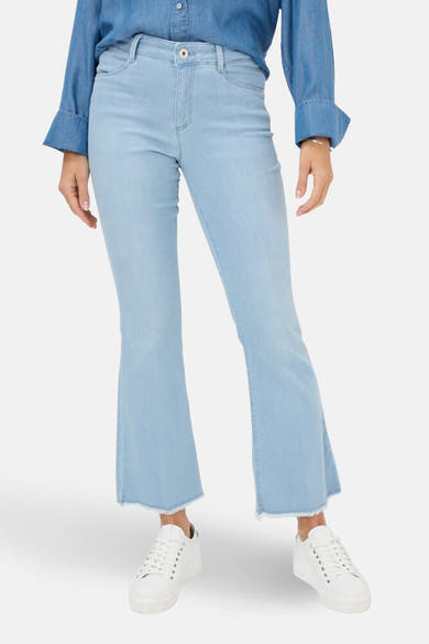 Jean slim en denim blanc de BRAX, porté avec une chemise en jean bleue et des baskets blanches.
