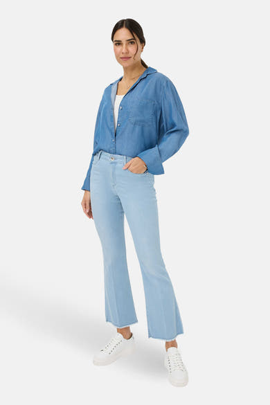 Jean slim en denim blanc de BRAX, porté avec une chemise en jean et des baskets blanches.
