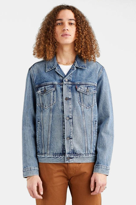 Veste en denim bleu de Levi's, avec poches poitrine et fermée par des boutons, portée avec un pantalon marron.
