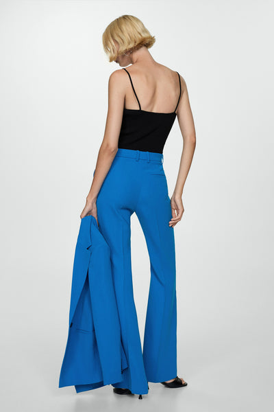 Pantalon de costume bleu de MANGO, coupe évasée, porté avec un débardeur noir fin.