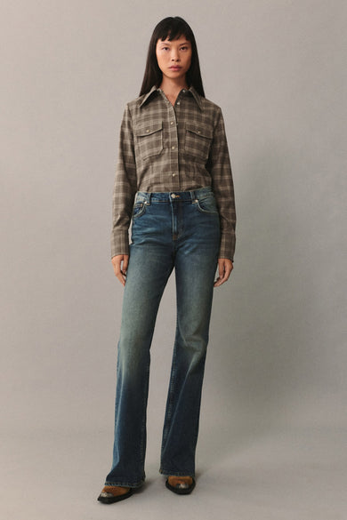 Jean bootcut bleu foncé de MANGO, porté avec une chemise à carreaux marron.
