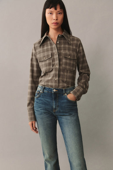 Jean bootcut bleu foncé de MANGO, porté avec une chemise à carreaux marron et beige.
