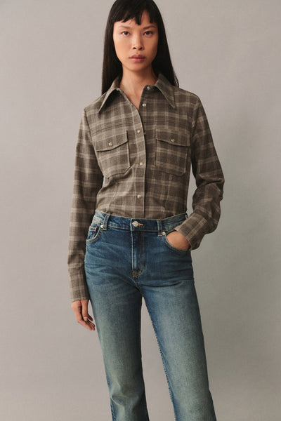 Jean bootcut bleu foncé de MANGO, porté avec une chemise à carreaux marron et beige.
