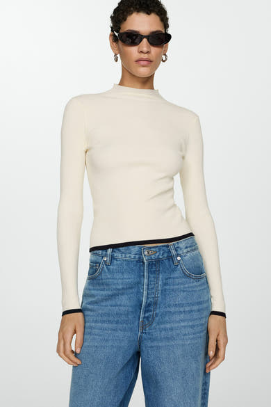 Witte trui met ronde hals van MANGO, in geribbelde breiwerk, gedragen met een high-waisted jeans.