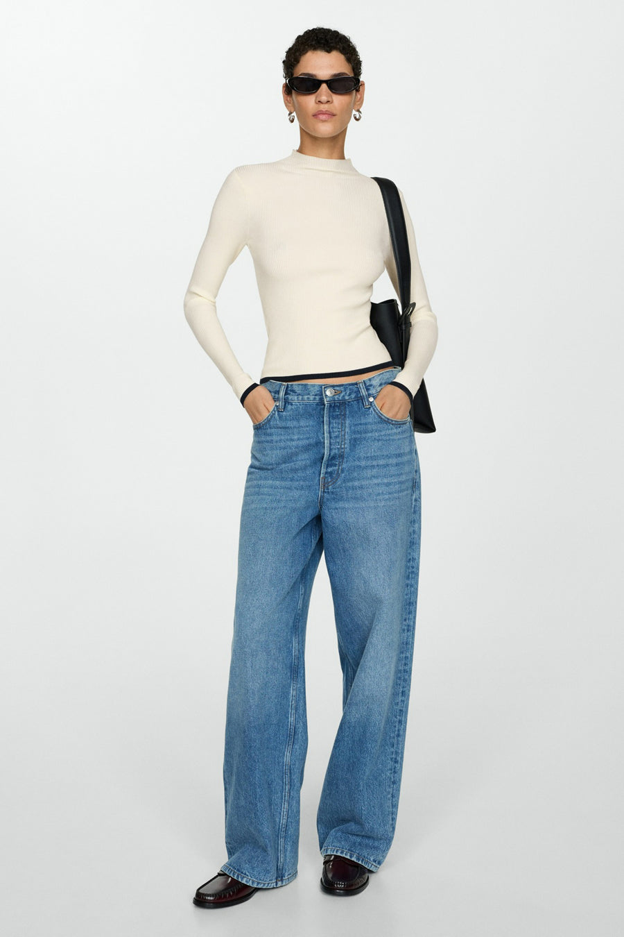 Witte trui met ronde hals van MANGO, gedragen met een wijde blauwe jeans en bordeauxrode loafers.