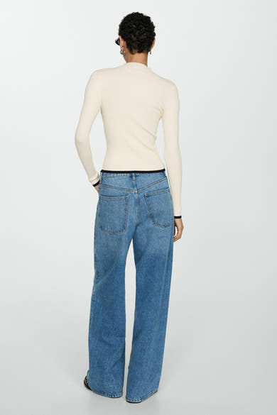 Pull à col rond blanc de MANGO, en maille côtelée, porté avec un jean taille haute.