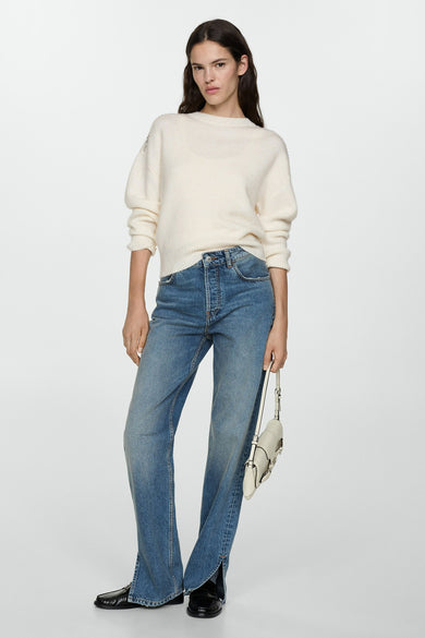 Witte ronde nekpull van MANGO, met decoratieve details op de schouders, gedragen met een jeans en zwarte schoenen.
