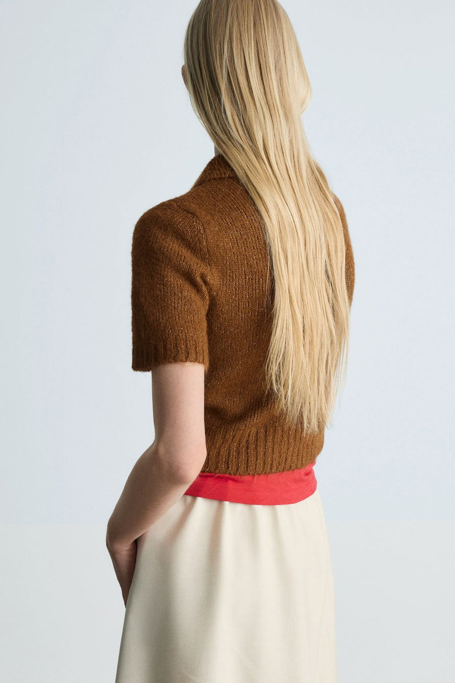 Bruine trui met col in het bruin van MANGO, gedragen met een beige rok en een rode top.