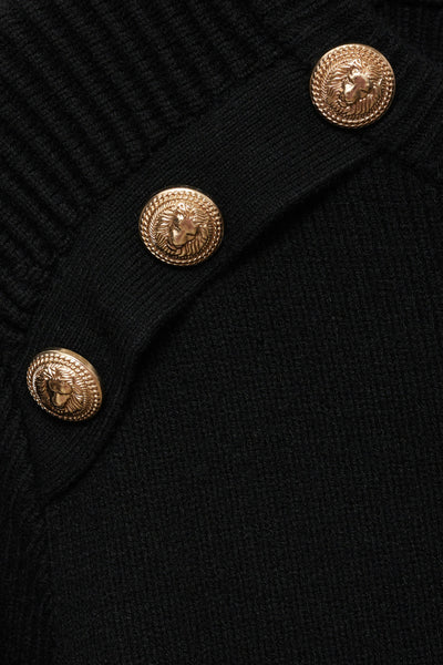 Pull à col rond noir de MANGO, avec des boutons dorés décoratifs sur l'épaule.
