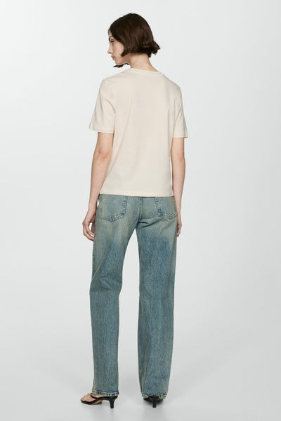 T-shirt beige à manches courtes de MANGO, porté avec un jean bleu ample et des escarpins noirs, vue de dos.