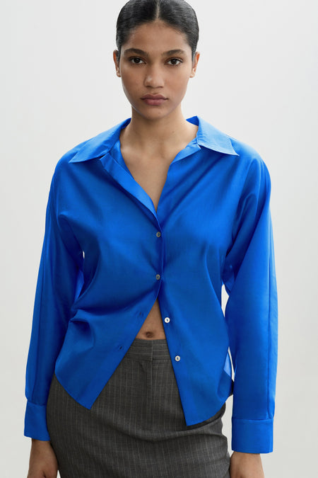Blauwe blouse met lange mouwen van MANGO, met een losse stijl en een vlecht detail in het haar.