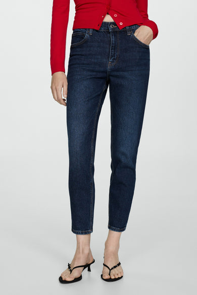 Jean Mom in donkerblauw denim van MANGO, gedragen met een rode top en zwarte stiletto sandalen.