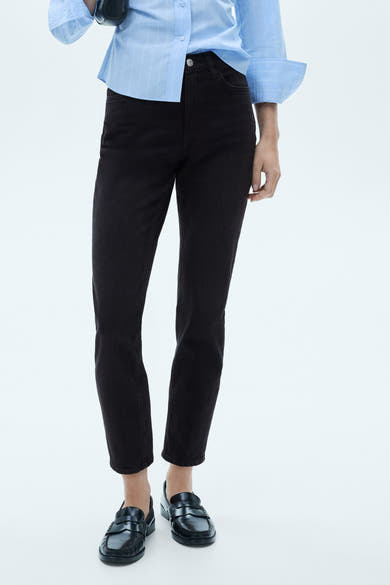 Zwarte mom jeans van MANGO, gedragen met een lichtblauw overhemd en zwarte loafers.