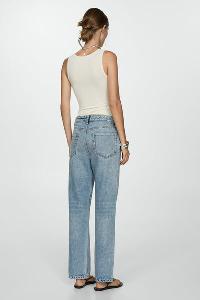 Jean en denim bleu clair de MANGO, coupe droite avec détail de bracelet argenté et sandales noires.
