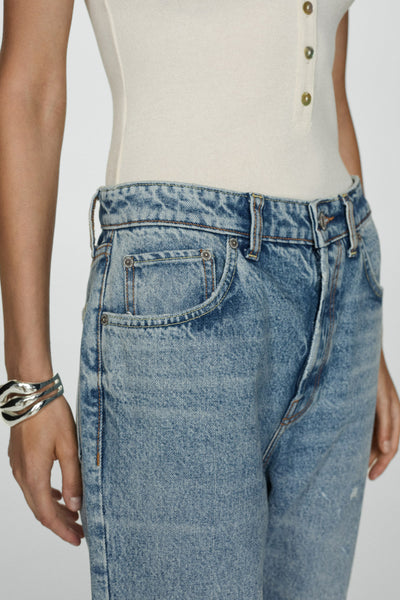 Skinny jeans in lichtblauw denim van MANGO, met zilveren armband en beige geknoopt topje.