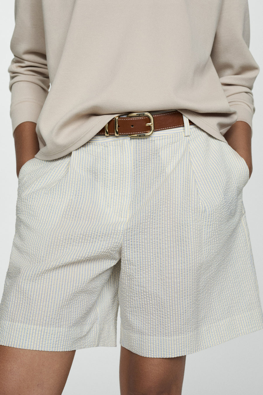 Ecru short van MANGO, gestreept, gedragen met een beige top met lange mouwen en sandalen met bandjes.