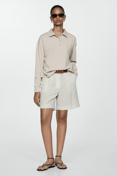 Ecru short van MANGO met bruine riem en fijne verticale strepen, gedragen met een beige polo en zwarte sandalen.
