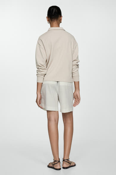 Short écru de MANGO, rayé, porté avec un haut beige à manches longues et des sandales à lanières.