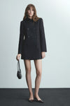Veste longue bleue de MANGO avec double boutonnage et une petite pochette noire.