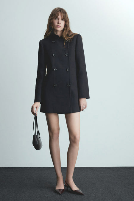 Veste longue bleue de MANGO avec double boutonnage et une petite pochette noire.