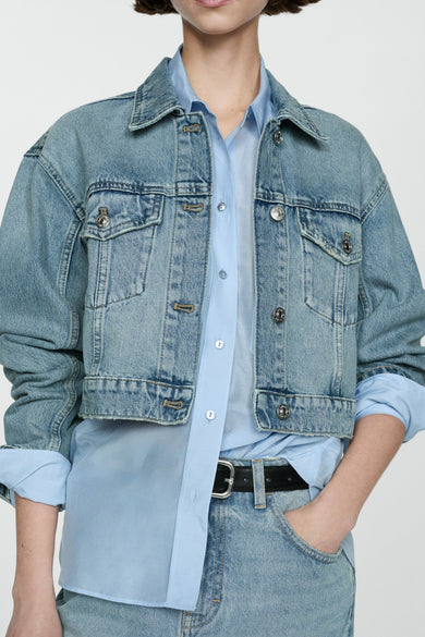 Veste en denim bleu moyen de MANGO, coupe courte avec poches à rabat et finitions usées.