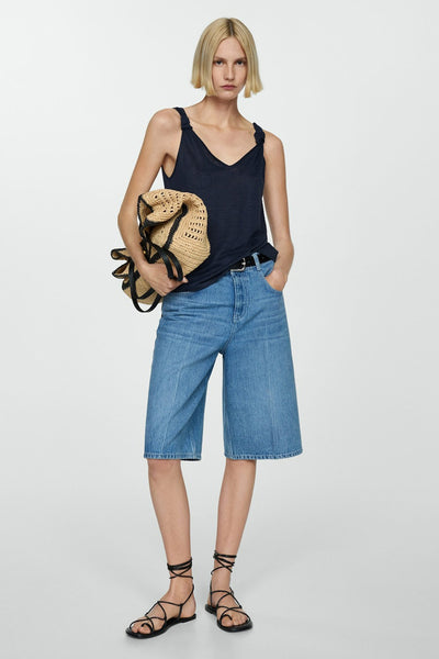 Navy blue sleeveless top with V-neck and tie straps, worn with denim bermuda shorts and black strappy sandals, full-length front view.