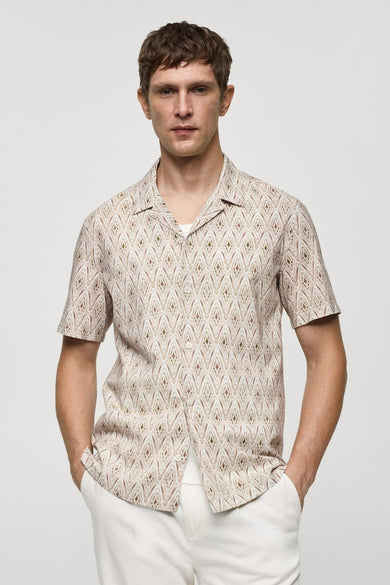 Chemise beige à manches courtes de MANGO avec un motif losanges et portée sur un t-shirt blanc.