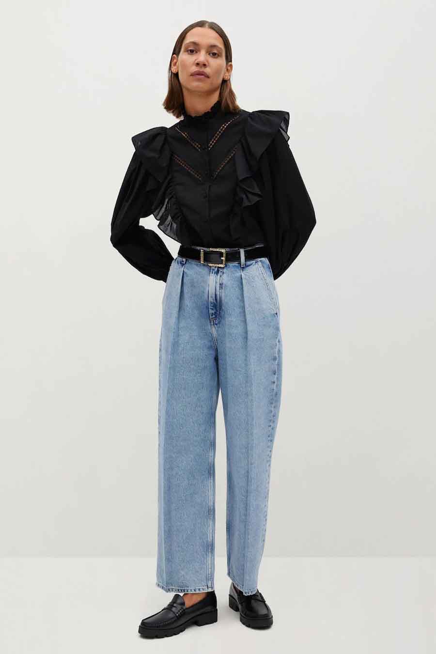 Chemise à manches longues noire de MANGO, avec des volants et des détails ajourés, portée avec un jean et des mocassins.