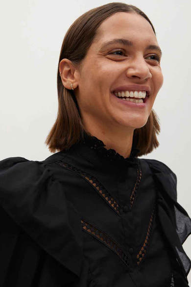 Blouse noire à manches longues de MANGO, avec détails ajourés et col montant à froufrous.