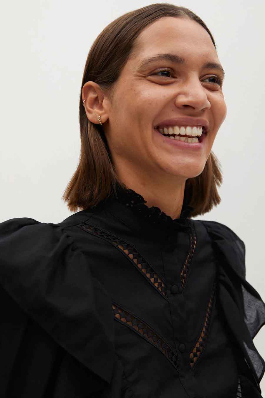 Blouse noire à manches longues de MANGO, avec détails ajourés et col montant à froufrous.