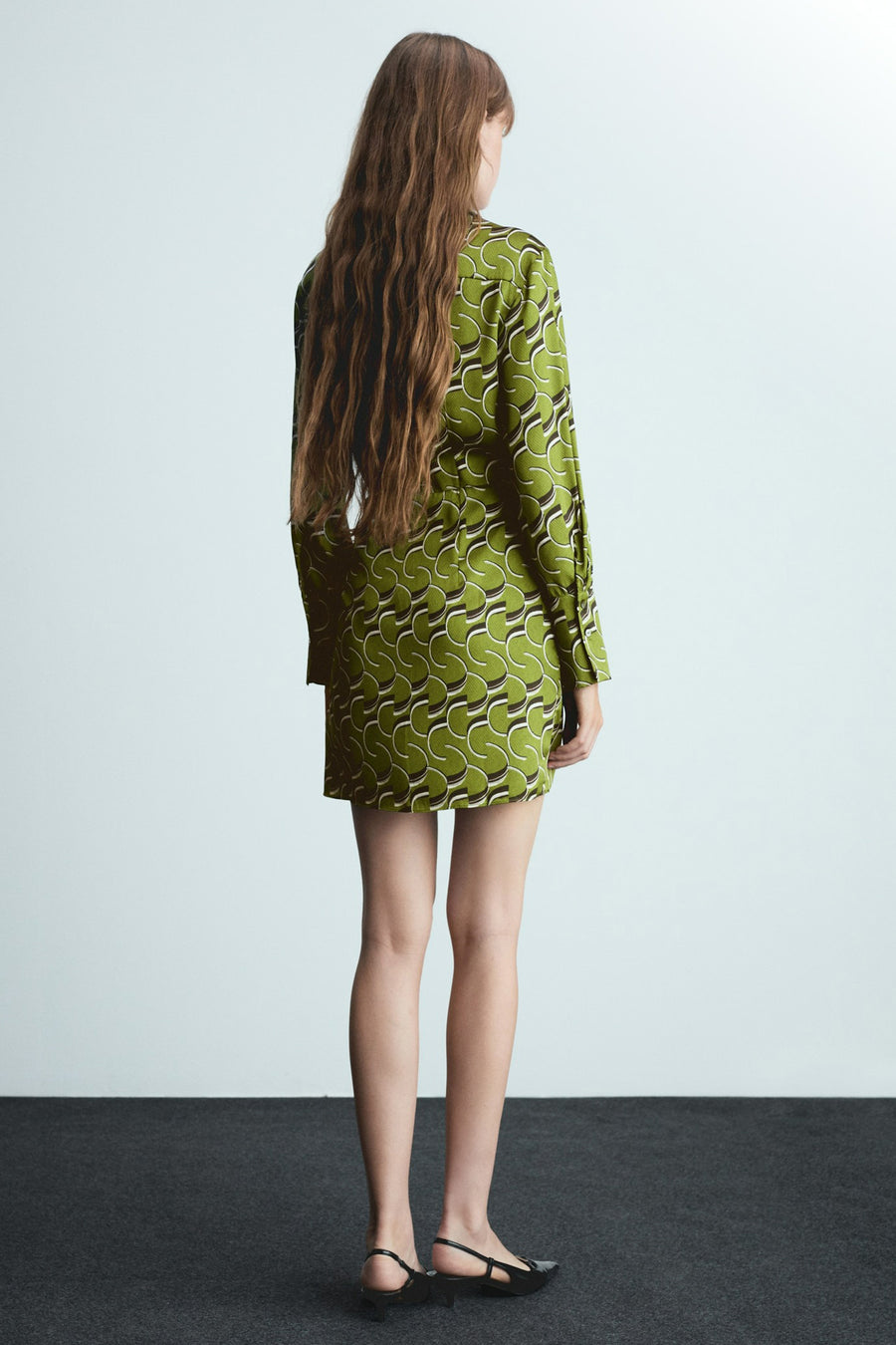 Groene jurk met lange mouwen van MANGO, met retro geometrisch patroon, gedragen met zwarte schoenen met lage hak.