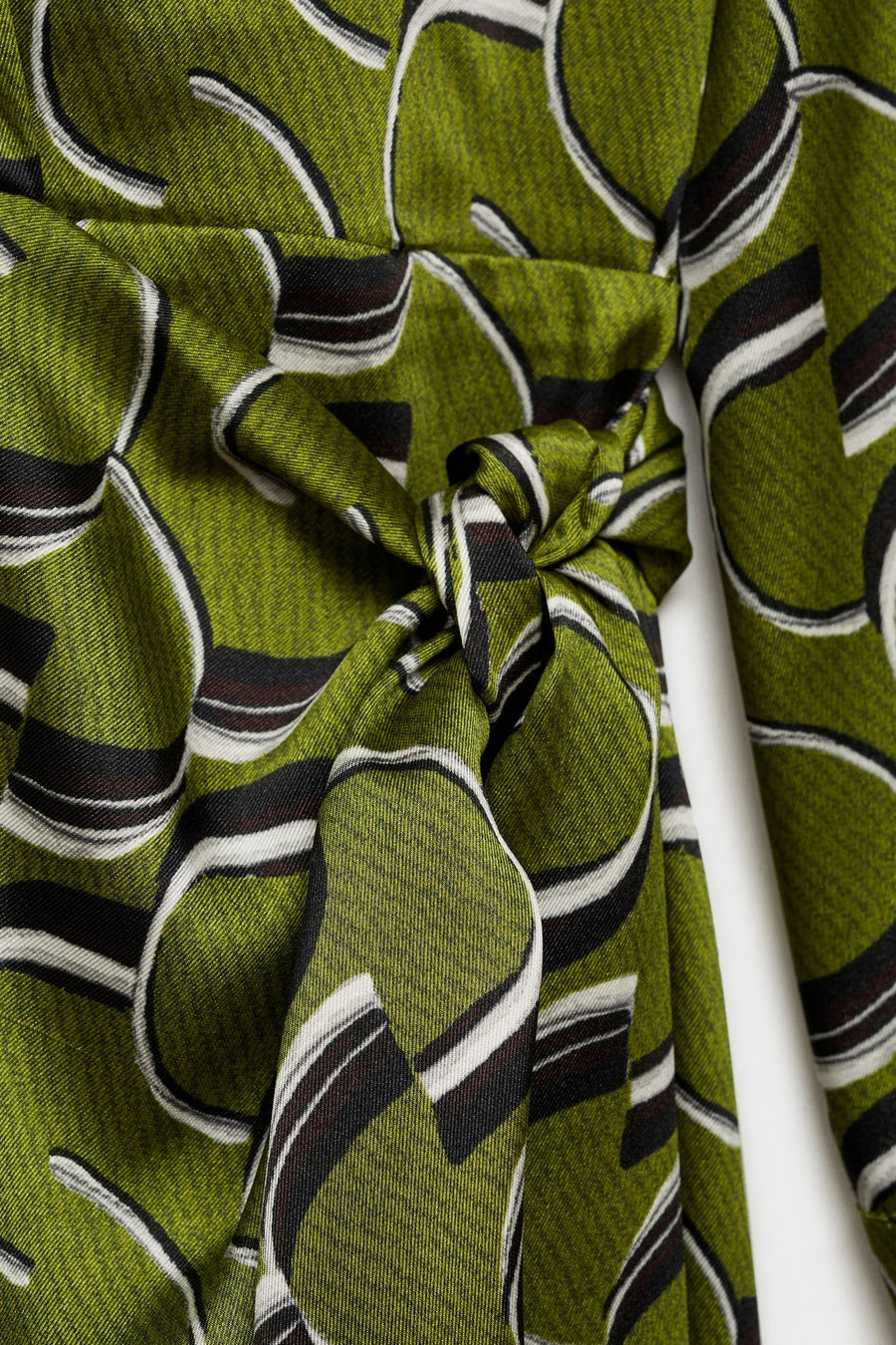 Groene jurk met lange mouwen van MANGO, met abstract geometrisch patroon en strikdetail in de taille.