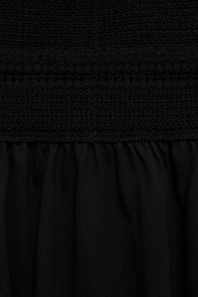 Zwarte jurk van MANGO, met ingewikkelde haakdetails en een geplooide textuur onder de tailleband.