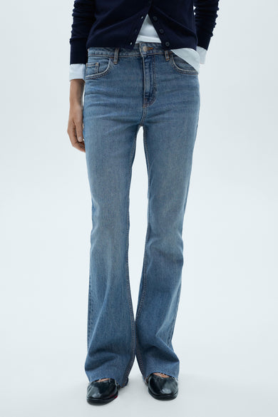 Middelblauwe flared jeans van MANGO, gedragen met een marineblauwe cardigan en zwarte ballerina's.