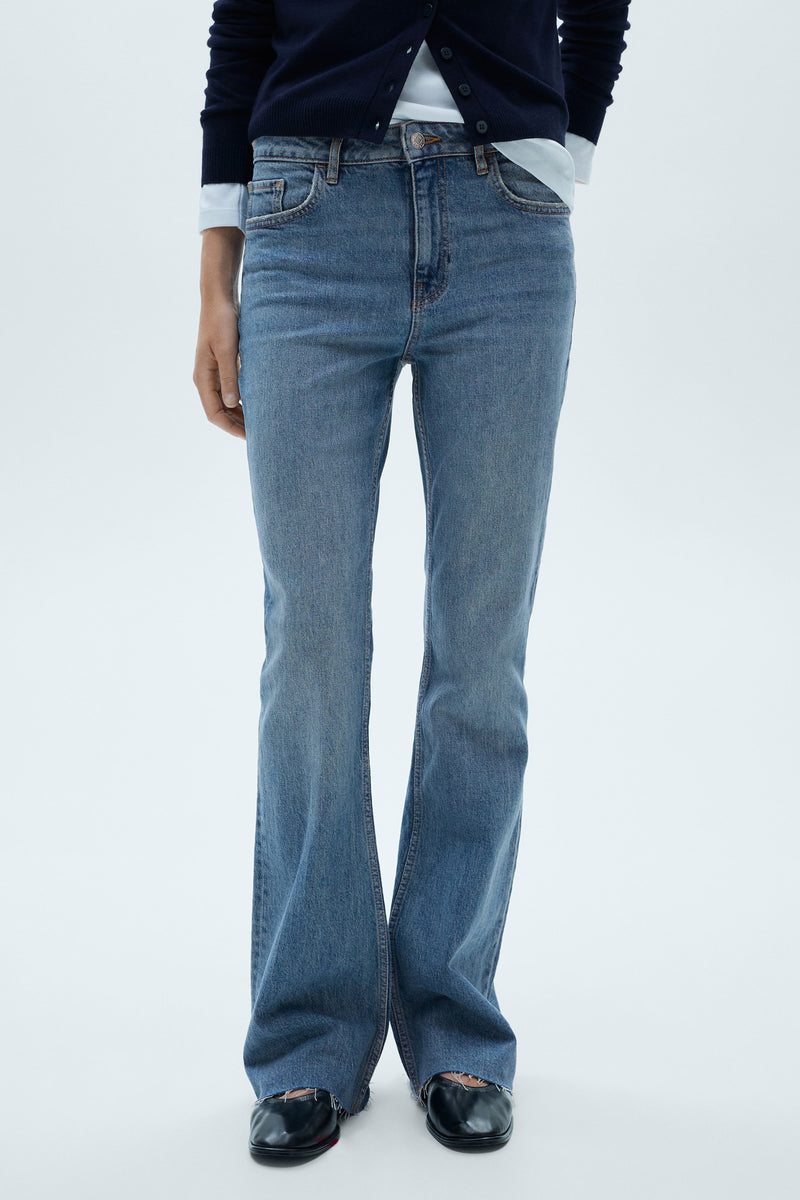 Middelblauwe flared jeans van MANGO, gedragen met een marineblauwe cardigan en zwarte ballerina's.