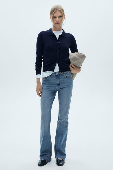 Middelblauwe flared jeans van MANGO, gedragen met een marineblauwe cardigan en een wit T-shirt.