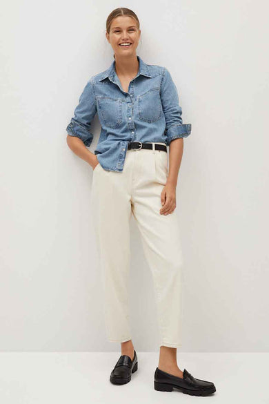 Blue denim long-sleeve shirt with chest pockets and rolled sleeves, worn with white trousers and black loafers, full-length front view.