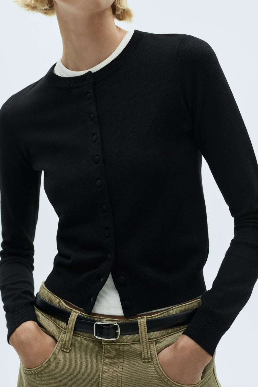 Gilet multicolore de MANGO, porté sur un t-shirt blanc et un pantalon kaki avec une ceinture noire.