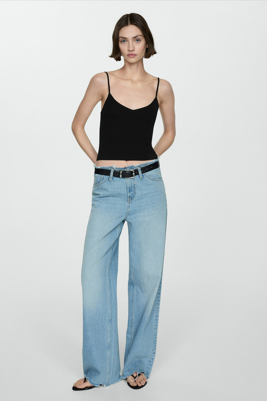 Zwarte top met dunne bandjes van MANGO, gedragen met een high-waisted jeans en een zwarte riem.