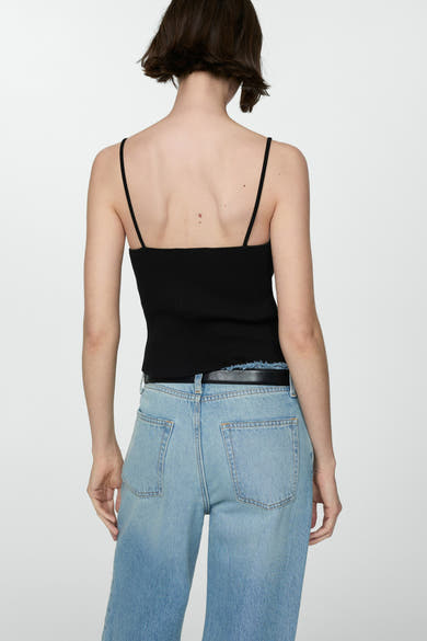 Zwarte top met dunne bandjes van MANGO, gedragen met een lichtblauwe jeans met hoge taille.