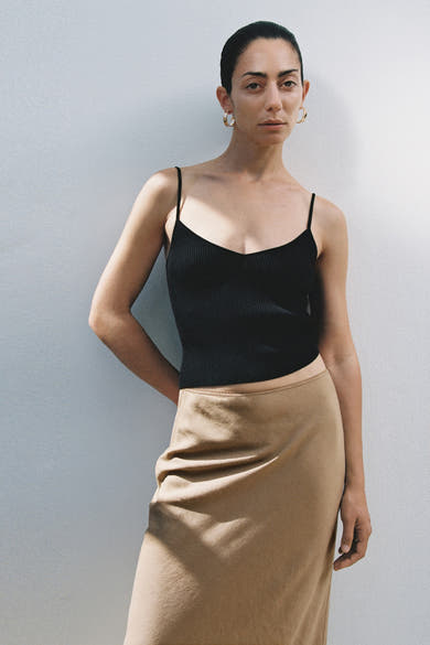 Zwarte top met dunne bandjes van MANGO, gedragen met een effen beige rok.